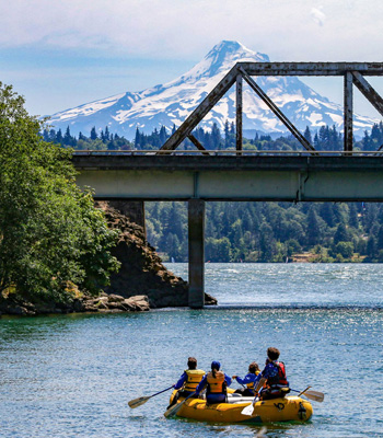 White water raft of people floating down the river with a mountain in the background