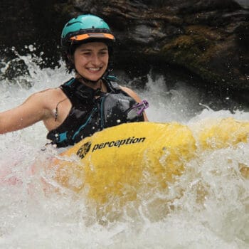 Action shot of Chloe Sligh whitewater kayaking with hand paddles.