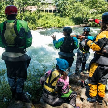 A group of kayak instructors discusses plans for running a rapid.