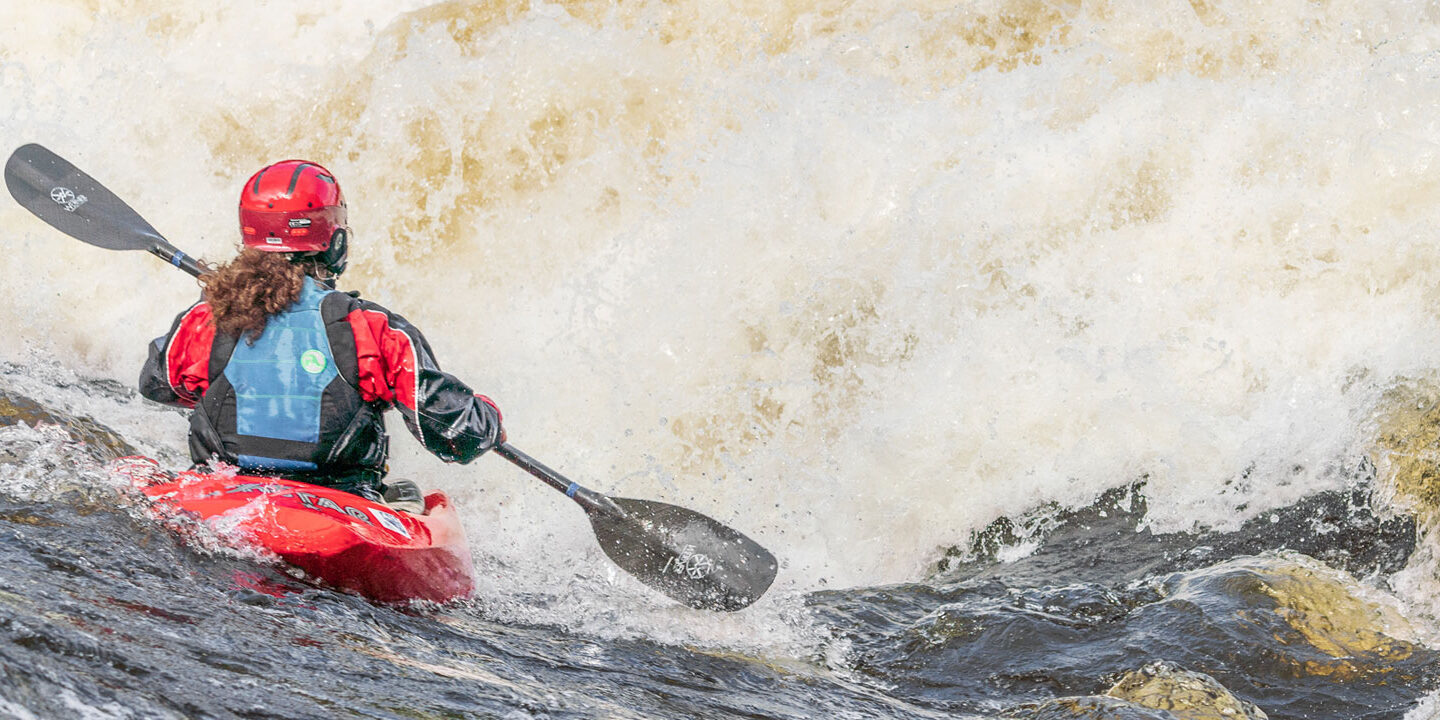 Kayaker going into large rapid