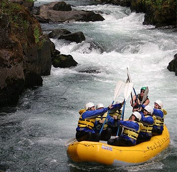 Group of people rafting down a river and tapping paddles in the air