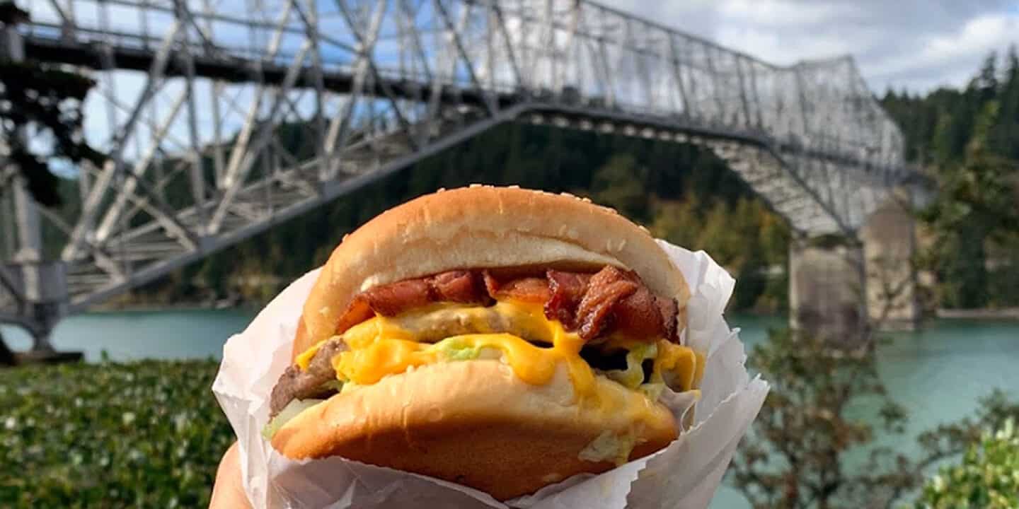 a cheeseburger with melting cheese in a wrapped with a bridge in the background