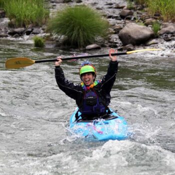 A kayaker on an Oregon kayaking course raises his paddle above his head to celebrate.