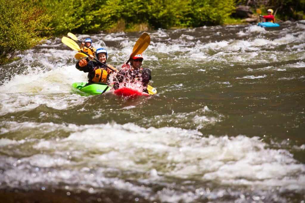 Three kayakers run a rapid during a beginner kayak lesson in Washington.