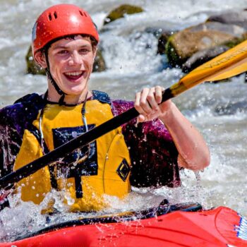 A kayaking student on a beginner kayaking course in Washington smiles while kayaking.