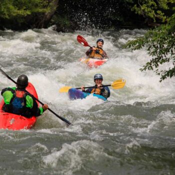 An instructor leads beginner kayakers through a rapid on an Oregon river kayaking course.