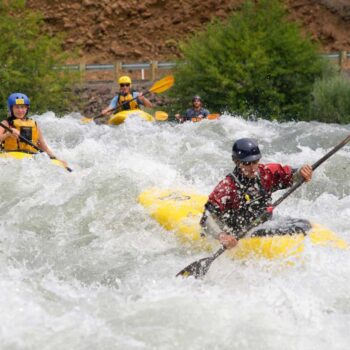 A kayaking instructor leads two students through a rapid on a beginner kayaking course in Oreogn.
