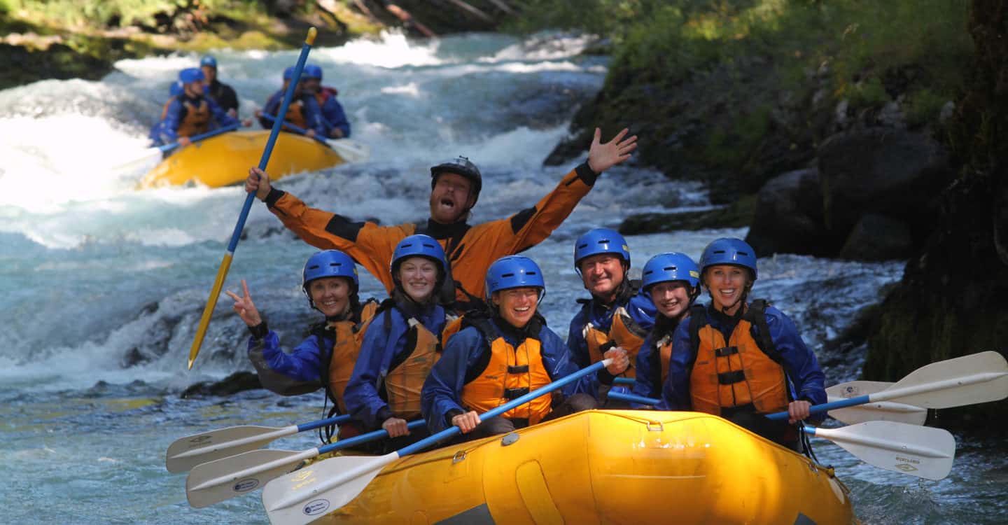 A raft guide celebrates while his crew smiles on a white salmon river rafting trip washington and oregon.