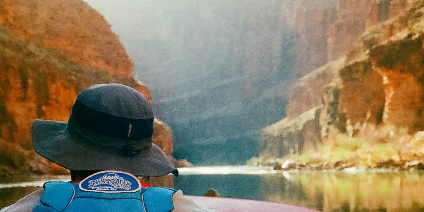 the back of a rafters head on calm waters through the canyon