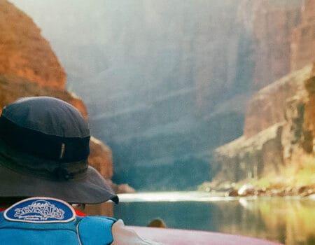 the back of a rafters head on calm waters through the canyon