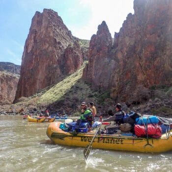 One rower and two passengers float in a gear raft with beautiful Owyhee River canyon scenery in the background.