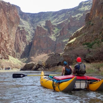 A rower rows a cataraft with one passenger in it on the Owyhee River during guide school.