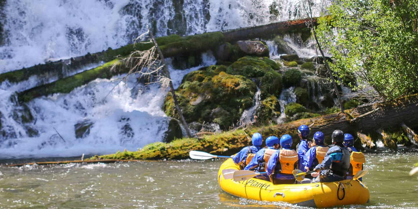 a raft full of people approaching a river hillside full of snow. Wet Planet Whitewater Washington Idaho Oregon