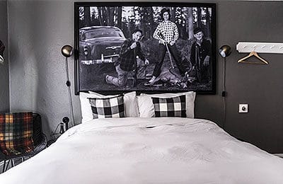 Bed with white comforter and historic image above the bed at Hood River Hotel. Wet Planet Whitewater in Washington, Idaho, Oregon