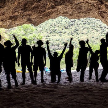 A group of rafters are seen in silouhette while making a silly pose in a cave during an Owyhee River rafting trip in Oregon.