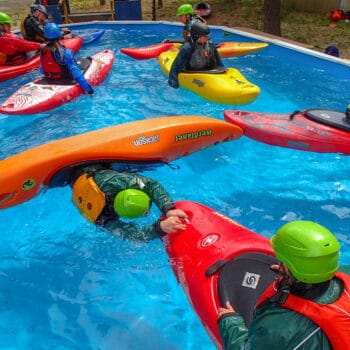 A student practices the t-rescue with an instructor during a kayak pool session.