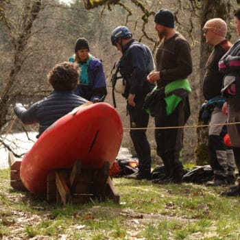 During a river rescue certification course an instructor demonstrates how to rescue a kayaker pinned in his kayak.