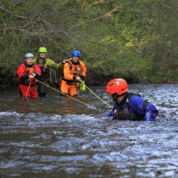 Students on a river rescue certification course in Oregon use rescue ropes to practice stabilizing a patient stuck in the river.