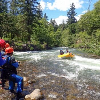 Students on a river rescue certification course in Washington use a rescue rope to belay a raft in the river.