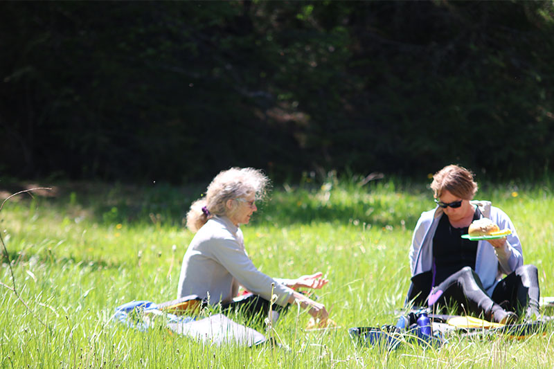 two rafters take a break for a picnic lunch in the green grass. Wet Planet Whitewater