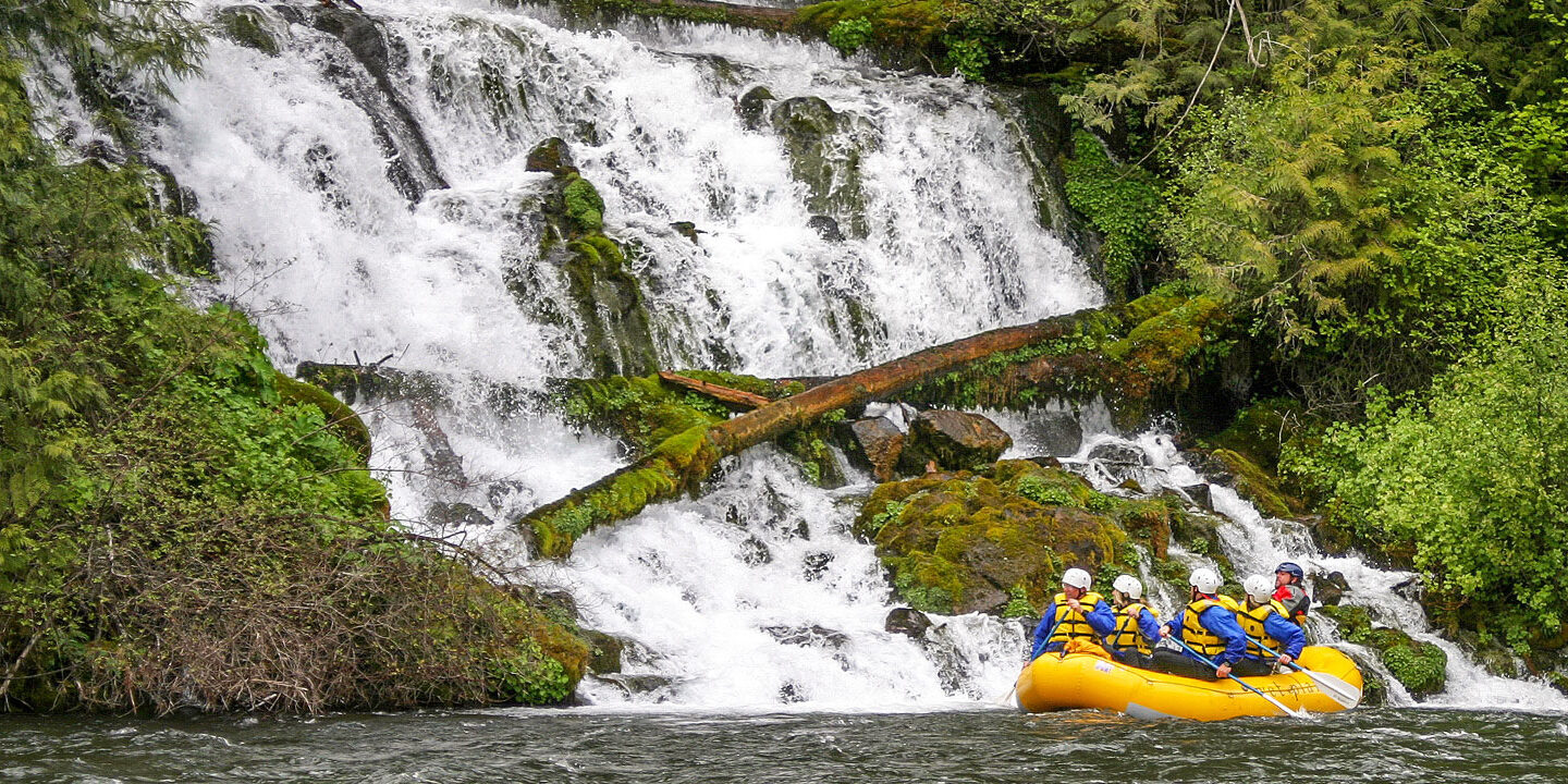 Group rafting along a mossy waterfall