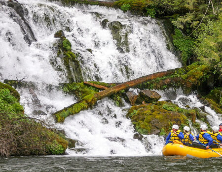 Group rafting along a mossy waterfall