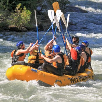 A group of rafters celebrates with a paddle high five on a Tieton River rafting trip