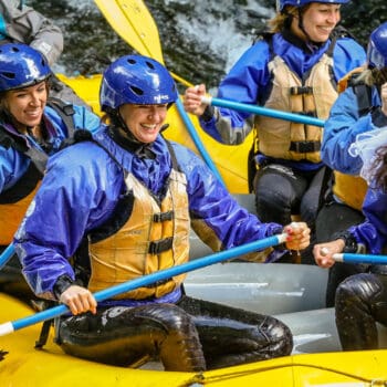 A group of women on a river rafting trip on the White Salmon river in Washington smile and laugh.