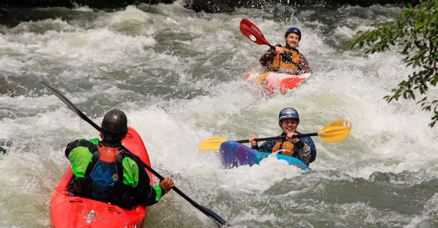An instructor leads two kayakers through a rapid on a beginner refresher kayak course.