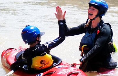 Kayak instructor gives high five to young student who took a kayak course. Wet Planet Whitewater in Washington, Idaho, Oregon