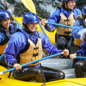 A group of rafters smiles after running a rapid on a wedding party trip. Wet Planet whitewater Oregon, Washington, and Idaho.