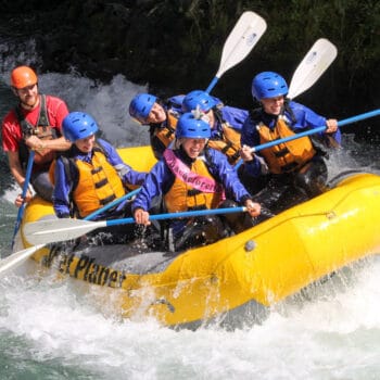 A group of women raft through Top Drop rapid, with one of them wearing a bachelorette banner.