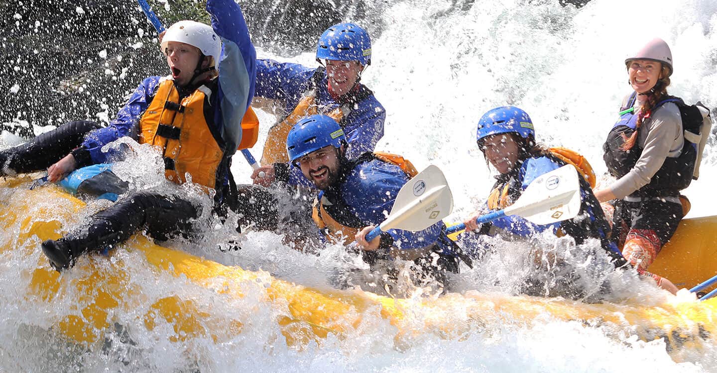 Group of rafters are excited and their raft guide smiles while splashing through Rattlesnake Rapid on a White Salmon River rafting trip in Washington Wet Planet Whitewater in Washington Oregon Idaho