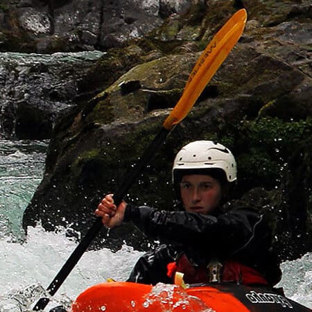 A woman kayaks through a rapid on an intermediate kayak instruction course.