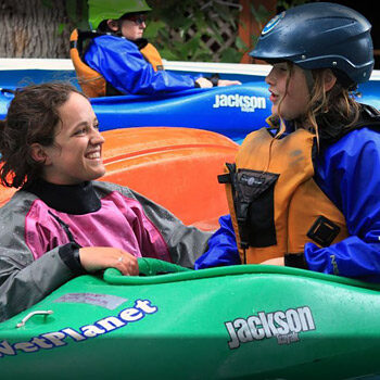 A young kayaker on the kids kayak camp sits in her kayak while her instructor stands next to her in the pool - Wet Planet kayak instruction Washington Oregon Idaho
