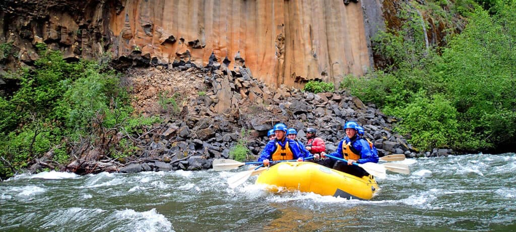 a group of rafters rafting the klickitat river at the base of a large rock