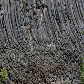 A group of rafters floats towering basalt cliff walls on a Klickitat River rafting trip.