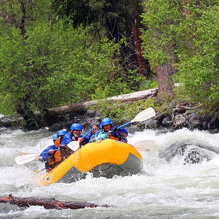 Rafting on the Klickitat River, a group of rafters paddle through waves.