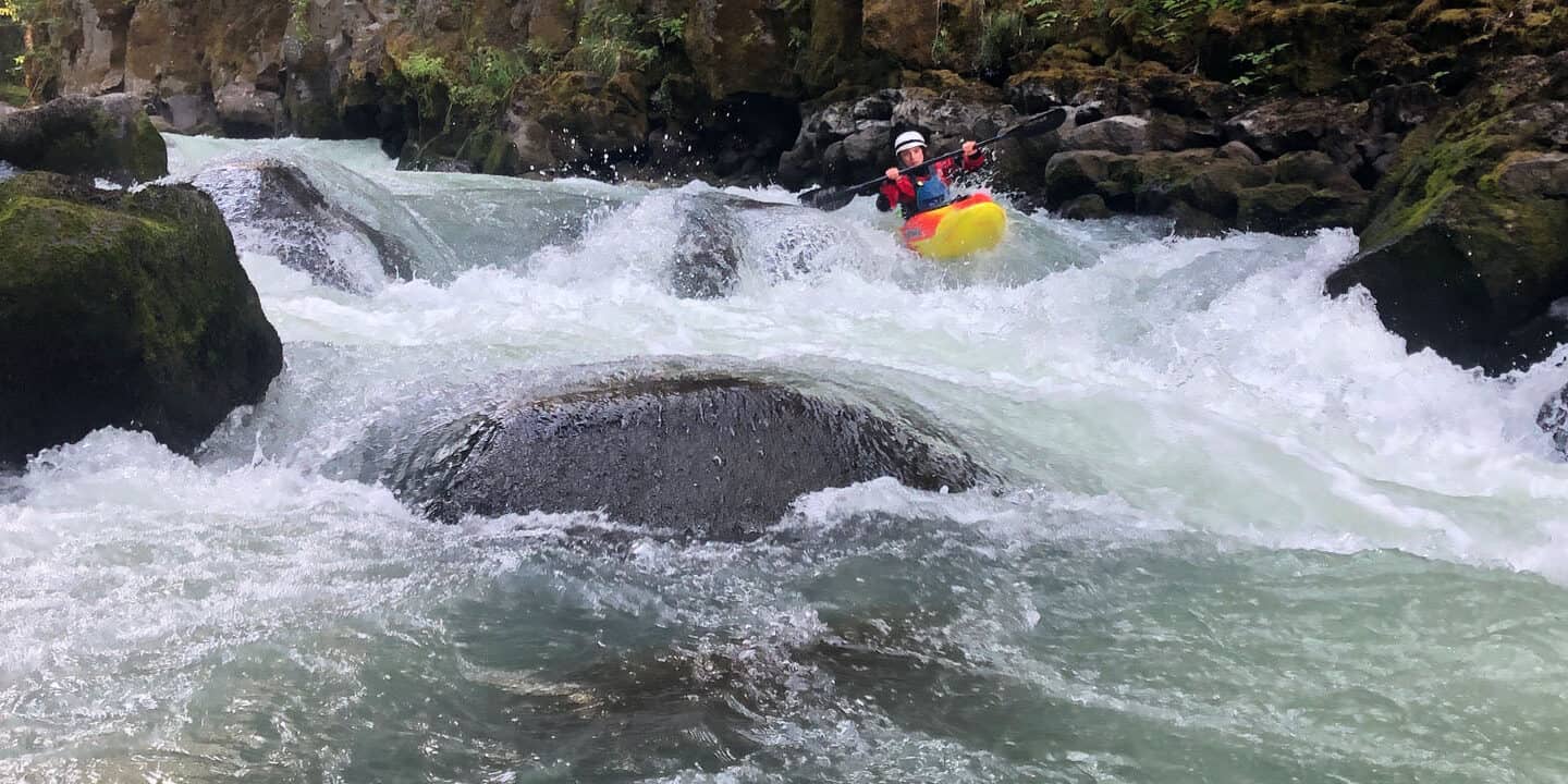 Person kayaking around big boulders
