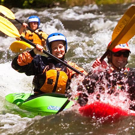 Three kayakers paddle a rapid on the Novice kayak instruction course on the Klickitat River in Washington.