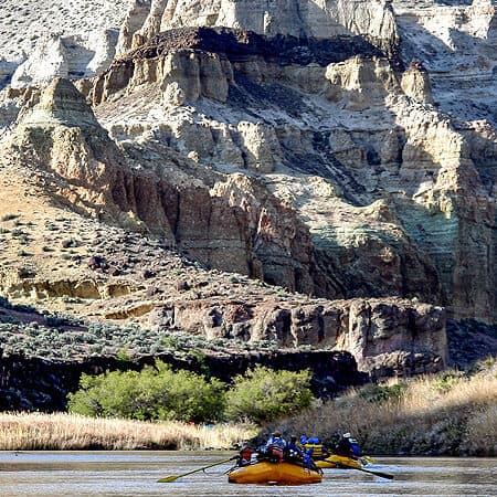 Two rafts float in front of towering cliff walls and amazing scenery on an Owyhee River rafting trip in Oreogn.