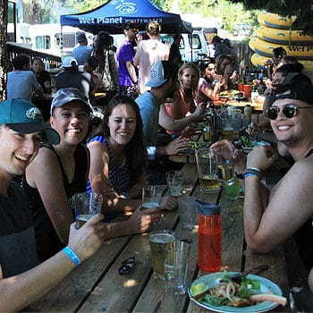 A group smiles to the camera while eating burgers at a raft and BBQ luch on the White salmon river in Washington.