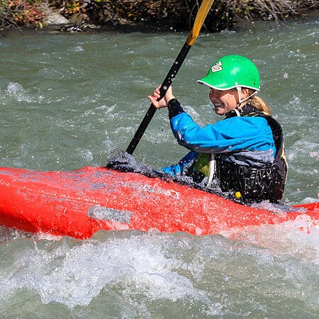 A female kayaking student paddles a rapid on a beginner kayaking course. Wet Planet Whitewater in Washington Oregon Idaho