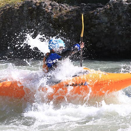 A kayaker is splashed by waves on a beginning kayak lesson.