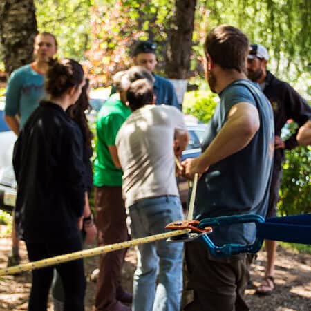 An instructor teaches students how to set up a mechanical advantage system on a river rescue course.