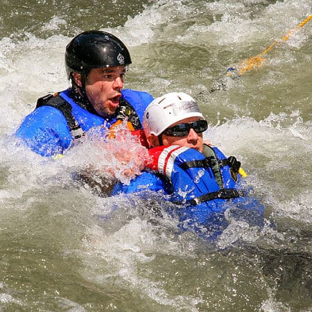 A student holds onto a patient in the river during a rescue simulation on a river rescue training cours.