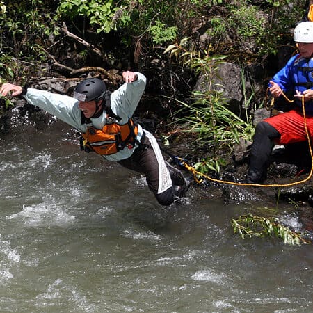 A student on a river rescue course RRC Pro jumps into the water to rescue an instructor during a rescue simulation.