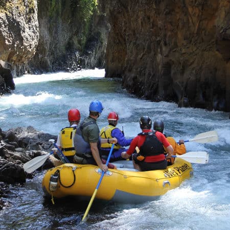 Rafters and guide look a head at the rapids between the rocks. Wet Planet Whitewater in Washington Oregon Idaho