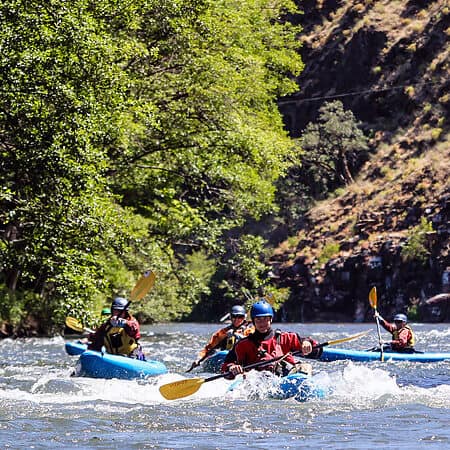 A group paddles sit on top kayaks on the river in Washington.