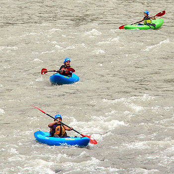 Three kayakers paddle a rapid on a Sit-on-top kayaking trip on the Klickitat River in Washington.